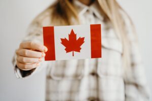 Meisje houdt Canadees vlaggetje vast, horend bij bericht over verhoging van het Working Holiday quotum